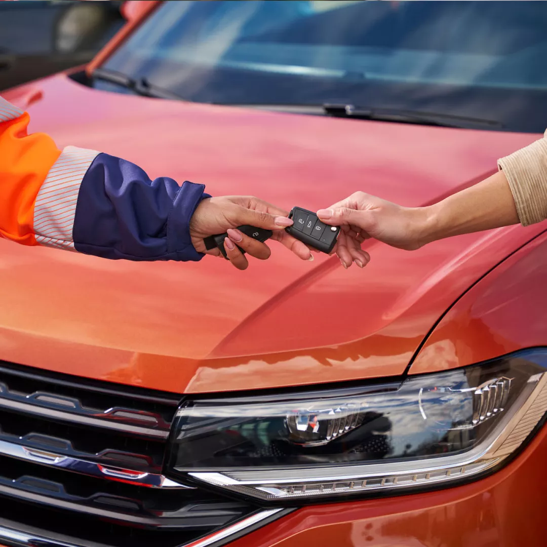 Detalle de dos manos sujetando una llave delante de un Volkswagen